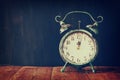 Vintage filtered image of old alarm clock on wooden table in front of black wooden background Royalty Free Stock Photo