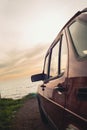 Vintage-filtered photo from the side of a 1990s classic red sports car with beautiful view of sunset by the sea Royalty Free Stock Photo