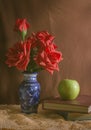 Vintage filtered rose in vase with apple and books.