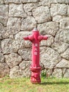 Fire hydrant in front of stone wall.