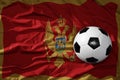 Vintage football ball on the waveing national flag of montenegro background. 3D illustration