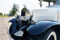A vintage Ford Model A stands in the parking lot. Front view of the bumper, headlights, hood.