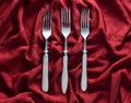 Vintage forks on a red silk tablecloth. Top view.