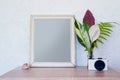Vintage frame, photocamera and tropical flowers on table. Wooden frame for photo shot or art print. Minimalist mockup with Royalty Free Stock Photo