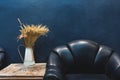 Vintage furniture and decoration, Dark blue wall with part of vintage leather armchair and vase with flowers on side table Royalty Free Stock Photo