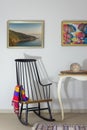 Vintage Furniture: Rocking chair and antique desktop clock on old style vintage table on background of off white wall