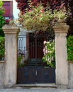 Vintage gate to the internal yard with metallic double door surrounded by flowers in Basque countryside, Spain