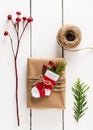 Vintage gift box in craft paper with mini handmade crocheted Christmas sock on white wooden background.