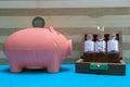 Vintage Glass Bottles of homeopathic pills in old open wooden box and Indian coin on pink piggy bank with blue surface and wood Royalty Free Stock Photo