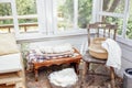 Vintage glass gazebo in the garden. Cozy retro interior with wooden benches and pillows. Pots with flowers and garden tools