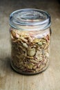 a vintage glass jar full of dried yellow and pink rose petals on a wooden table Royalty Free Stock Photo