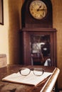 Vintage glasses on old book, old clock in background Royalty Free Stock Photo