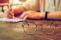 Vintage glasses,on wood table ,Man holding a pen  writing the  letter paper with sunset background. Copy space for you text Royalty Free Stock Photo
