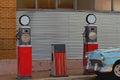 Vintage globe gas pumps by an old car. Royalty Free Stock Photo
