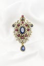 Vintage gold brooch with precious stones on white silk