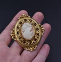vintage gold cameo brooch on a woman's hand, old retro jewelry Royalty Free Stock Photo