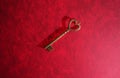 Vintage gold key with heart shaped top on red textured background Royalty Free Stock Photo