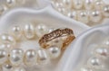 Vintage gold ring with diamonds lying on a white silk fabric, next to it are white pearls.diamond engagement rings on marriage Royalty Free Stock Photo