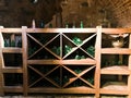 Vintage green empty wine and beer glass bottles in a wine cupboard with shelves in an old medieval bricked stone cellar Royalty Free Stock Photo