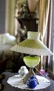 A Vintage Green Lamp With A Lace Edged Shade