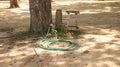 Vintage Green Water Hose and Red Valve in the Garden under Big Tree with Old Rustic Wooden Stool Royalty Free Stock Photo