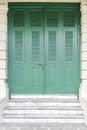 Vintage green wooden door made of plank with window shutter and  locked padlock on the cement wall yellow color with style Royalty Free Stock Photo