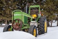 Vintage green and yellow tractor in snow drift in Saskatchewan, Canada