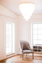 Vintage grey armchair in a light classic interior with big window and beautiful crystal chandelier in a room. Copy space. Royalty Free Stock Photo