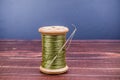 Vintage grunge wooden green thread spool with needle Royalty Free Stock Photo