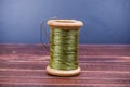 Vintage grunge wooden green thread spool with needle Royalty Free Stock Photo