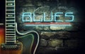 Vintage guitar and a neon inscription Blues on the background of an old brick wall. Concept music.