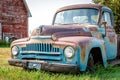 A vintage half ton pickup truck in front of a red barn on the prairies Royalty Free Stock Photo