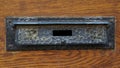 Vintage hand hammered mail box or letter slot in an old wooden door