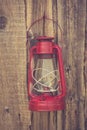 Red vintage handle gas lantern on rustic wooden wall.