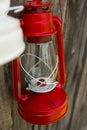 Red vintage handle gas lantern on rustic wooden wall. Royalty Free Stock Photo