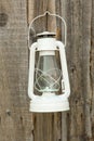 White vintage handle gas lantern on rustic wooden wall. Royalty Free Stock Photo