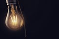 Vintage hanging light bulb with switch over dark background Royalty Free Stock Photo