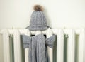 Vintage heating radiator with gray wool knitted winter hat and scarf.