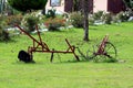 Vintage heavily used partially rusted agricultural farming equipment in shape of small plow now used as garden decoration