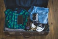 Vintage hipster traveler packing open suitcase on a wooden board with clothing, film-camera and mobile Royalty Free Stock Photo