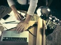 Vintage hipster wooden desktop top view, male hands using a laptop and holding a pencil Royalty Free Stock Photo