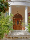 A vintage house entrance stairs with natural wooden arched double doors and potted plants