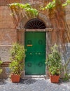 A vintage house exterior with green entrance arched door on ocher wall and flower pots, Trastevere old district, Rome. Royalty Free Stock Photo