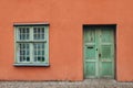 A vintage red house with old green door and window. Ancient wooden door in old building wall. Royalty Free Stock Photo
