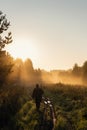Vintage hunter walks the forest road. Rifle Hunter Silhouetted in Beautiful Sunset or Sunrise. Hunter aiming rifle in Royalty Free Stock Photo