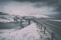 Vintage image of winter road and bridge between Lofoten Islands, moody dramatic landscape
