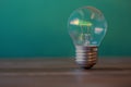 Vintage incandescent light bulb stands free and vertically on a dark wooden table. The photo has free space and the background is