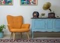 Retro orange armchair, vintage wooden light blue sideboard, old phonograph gramophone, vinyl records and illuminated table lamp