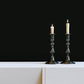 Vintage iron candlestick with burning candles in black interior.