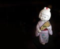 Vintage Japanese ceramic doll on dark background